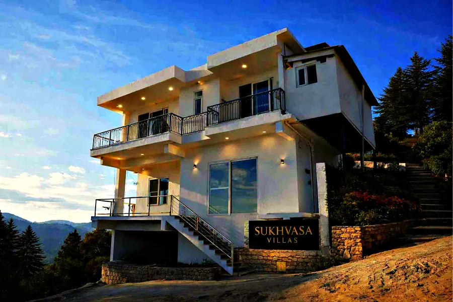 The white three-storey exterior of Sukhvasa Villas on the Beolia ridge above Shimla, framed by deodar pines