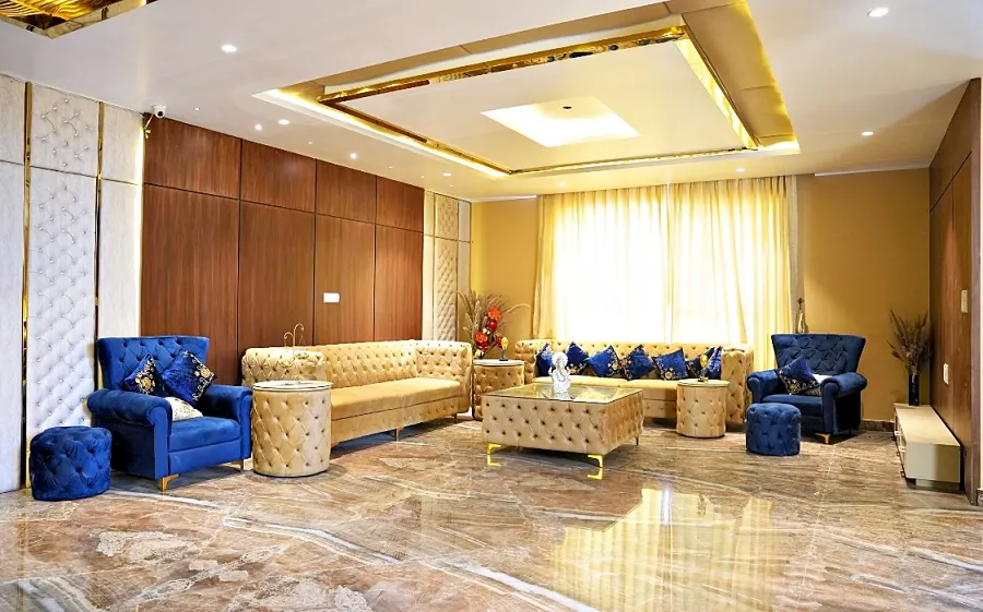 Sitting area with blue velvet armchairs and full-height curtained windows