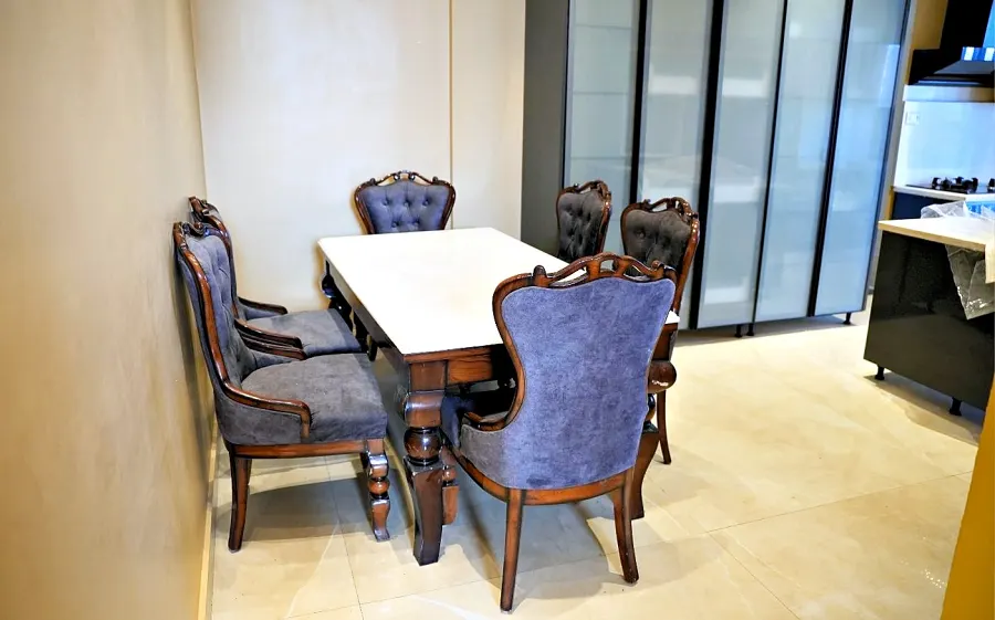 Carved dining table with upholstered chairs beside a window
