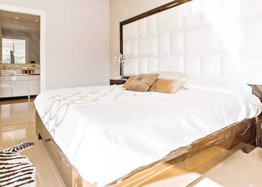 Valley View bedroom with a wide bed against a tall padded white headboard and a bedside lamp