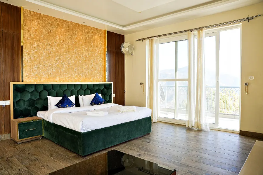 Executive bedroom with an emerald buttoned bed frame, blue cushions and glass doors onto the balcony