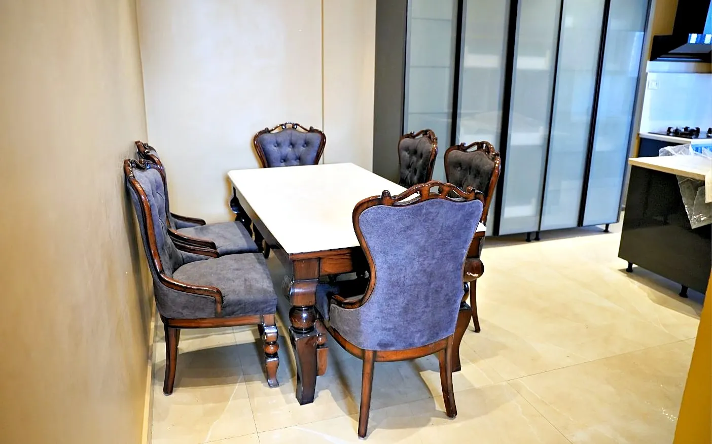 Carved dining table with upholstered chairs beside a window